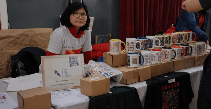 a woman manages a stall of mugs and other items to buy