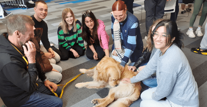 a group of students play with a therapy dog