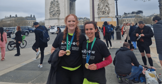 two marathon runners with medals in front of the Arc de Triomphe