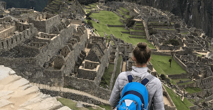 woman with rucksack looking out at Machu Picchu