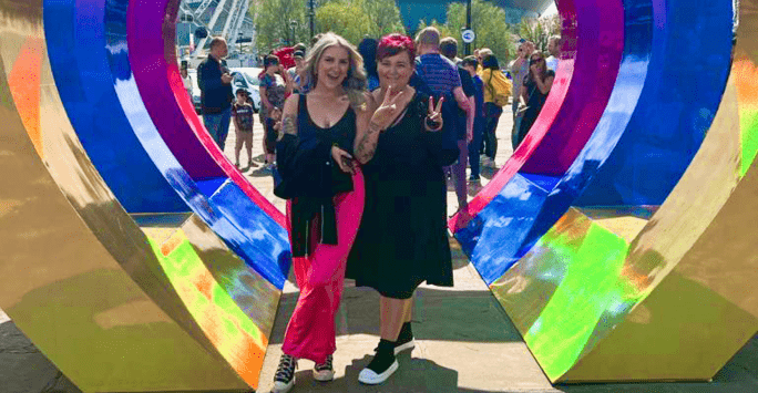 Two women pose at heart shaped Eurovision sign at Albert Dock