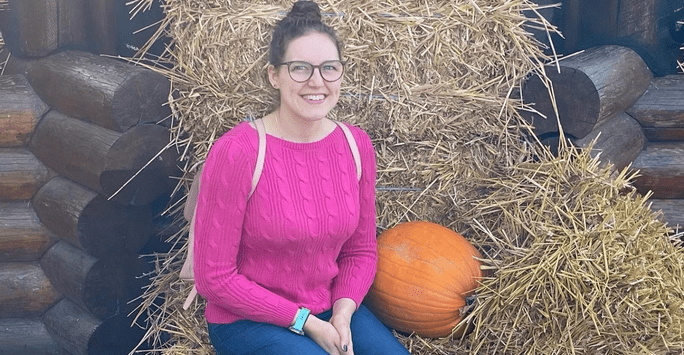 woman sitting in a haystack with pumpkins