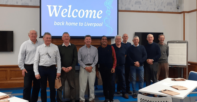a group of people in front of a slide that says welcome home to Liverpool