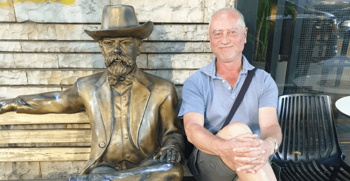 man sitting with bronze statue