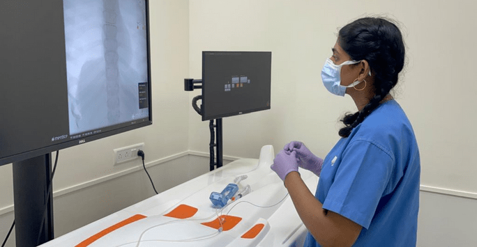 a student doctor in scrubs works with technology