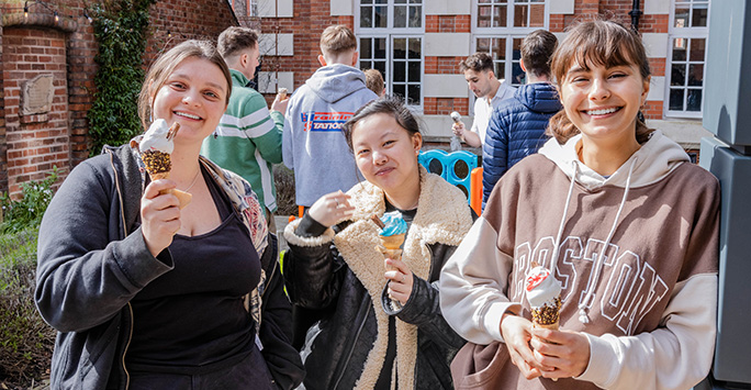 Three students smiling with ice cream in the garden
