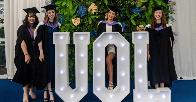 graduates pose with UOL letters