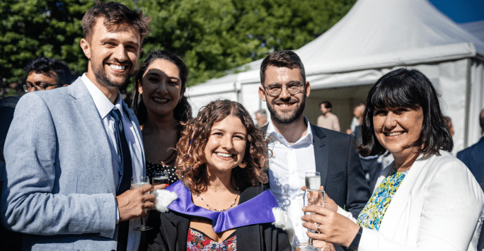 a graduate and her family smile in the sunshine