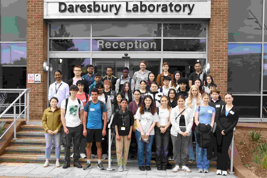 A group of people stands outside the Daresbury Laboratory, engaged in conversation and enjoying the outdoor setting.