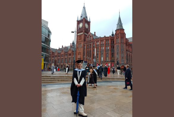 image of rebecca sheppard stadning outside in her graduation gown with the VGM in the background