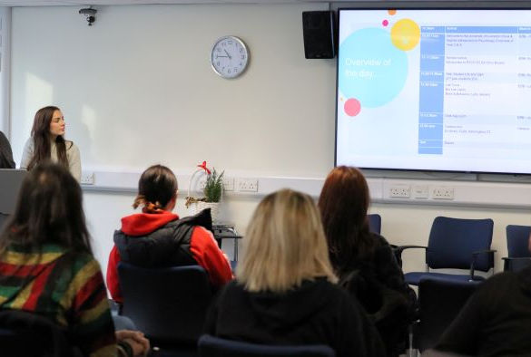 Students sitting in chairs listen to a welcome talk in a seminar room