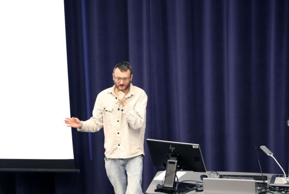 Dr Alexis Makin delivers a talk in front of a projection screen