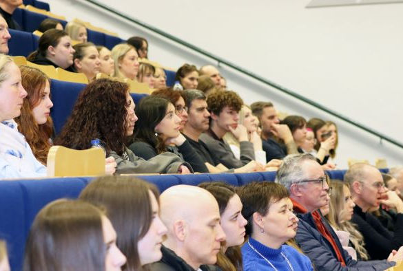 Students sit in rows of seats watching a welcome talk