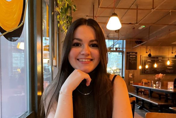 Second year psychology student Beth Witham sitting at a table smiling