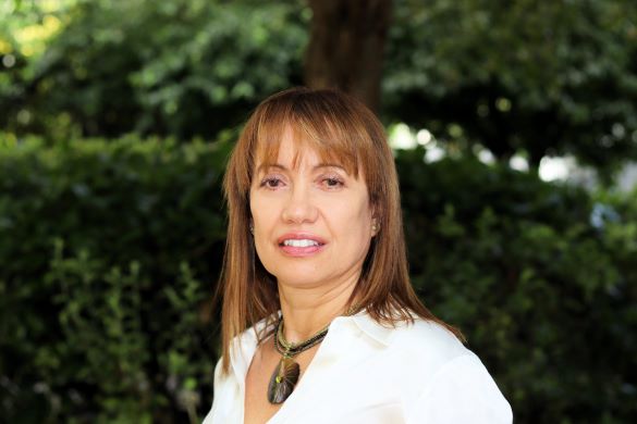 Dr Idalmis Santiesteban in a white shirt standing in front of trees