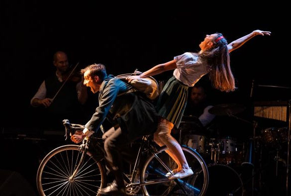 Two actors ride a bike onstage