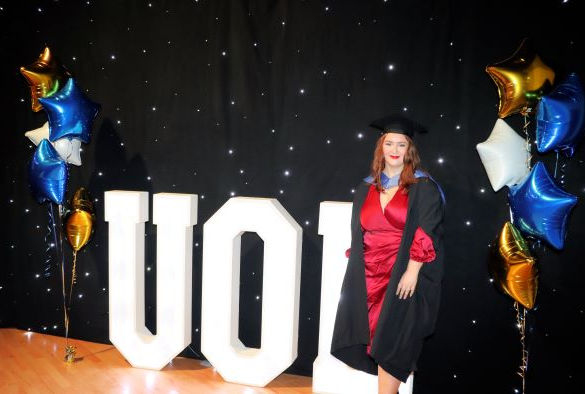 Student in red dress by light up UOL sign