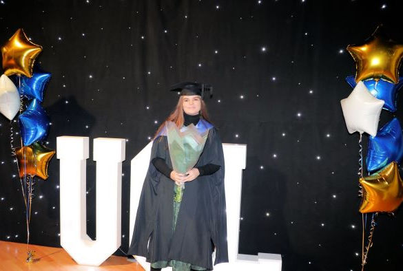 Student in Graduation robes by UOL sign