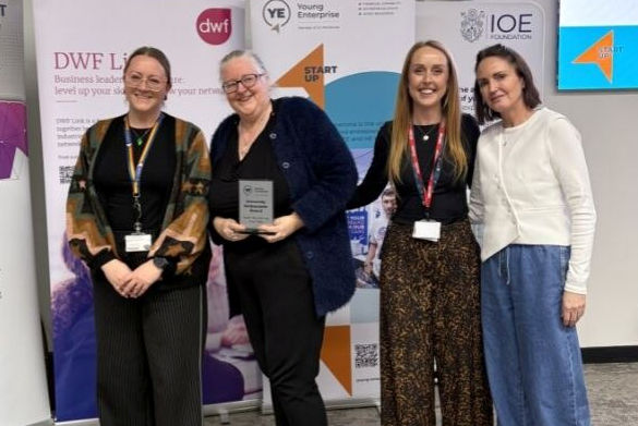 University staff stand in front of a banner holding an award