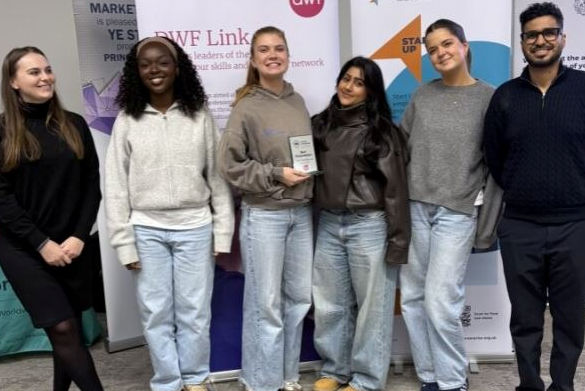 Five students stand in front of a banner holding an award