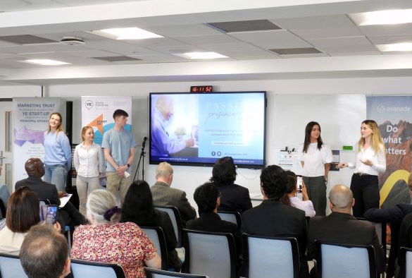 Students stand either side of a projection screen