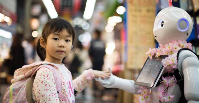 Photo of a young girl holding hands with a robot