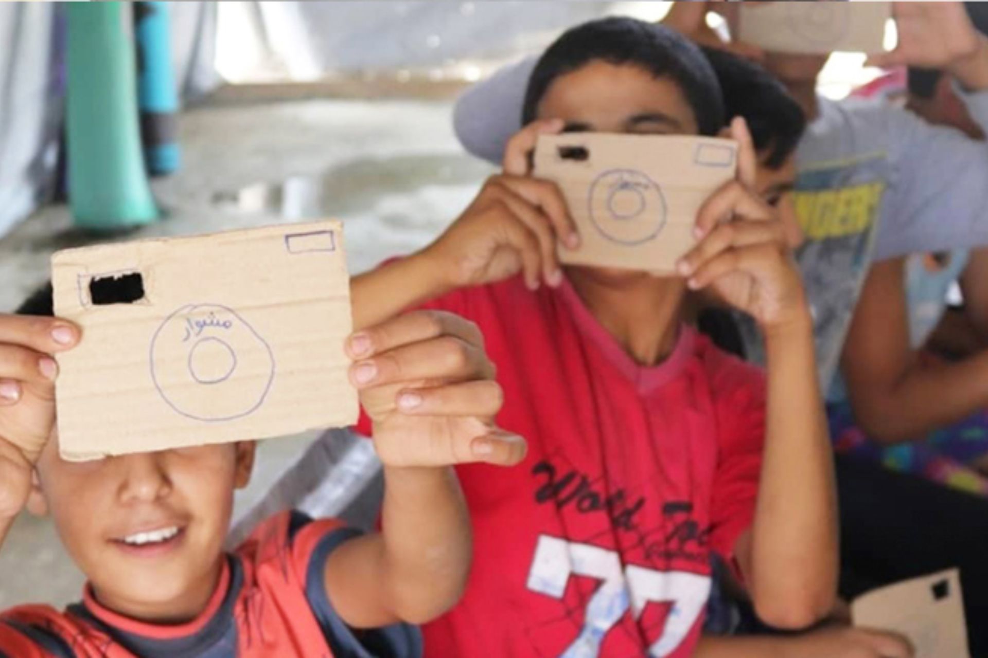 Children holding up cameras made of cardboard