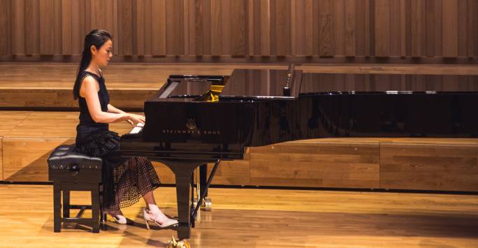 Student playing piano in the Tung Auditorium