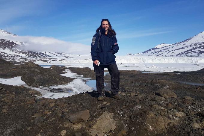 Dr Whitby standing in front of snow-capped mountains in Greenland