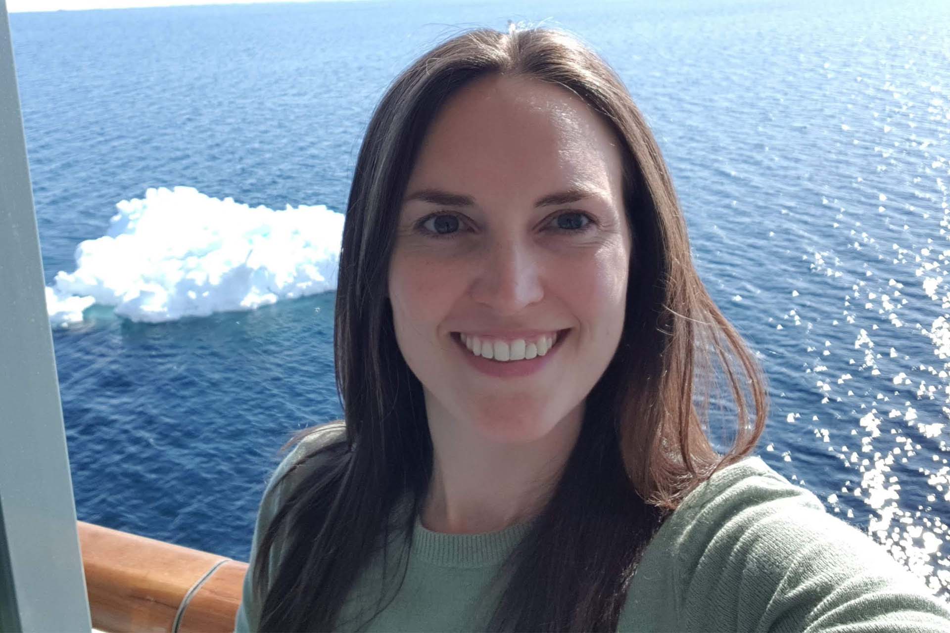 Dr Hannah Whitby taking a selfie on a boat with a glacier in the background