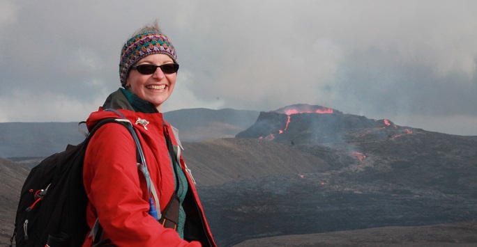 Dr Janine Kavanagh standing near a smouldering volcano
