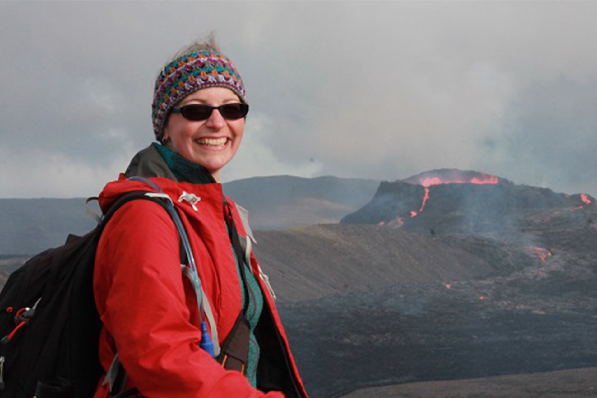 Dr Janine Kavanagh standing near a smouldering volcano