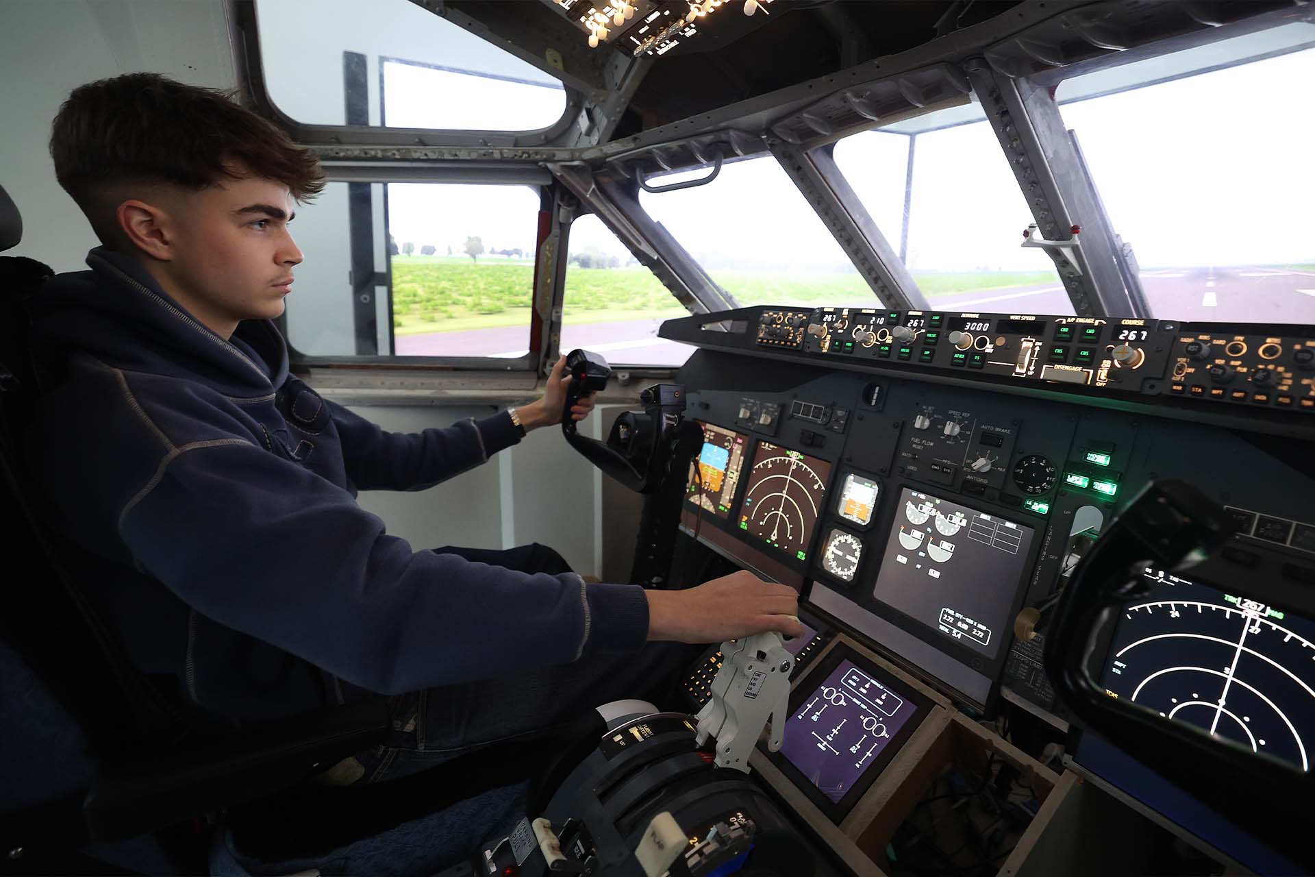 A school age student sits in the cockpit of a helicopter simulator