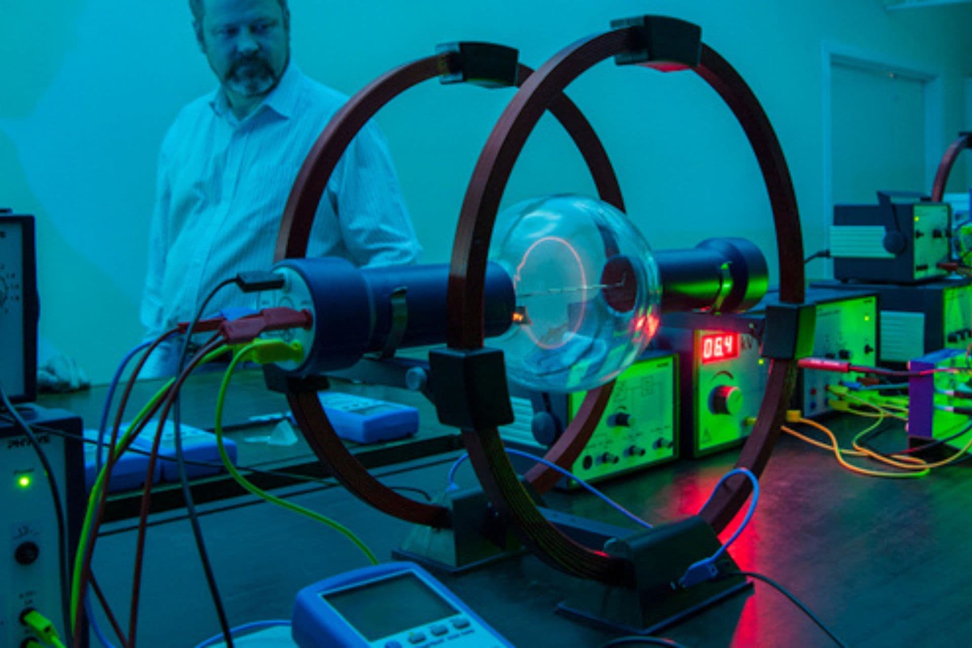 A man in a lab standing next to a large circular device conducting experiments or research.