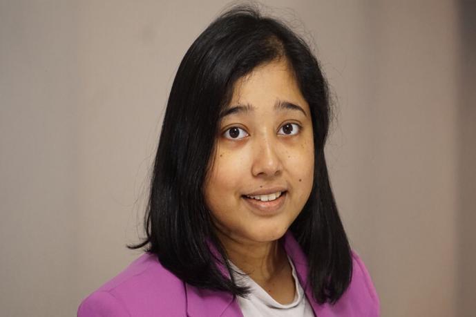 A headshot image of Dr Sen standing against a mauve backdrop