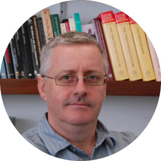 A photo of Professor Barry Godfrey in front of a bookcase.