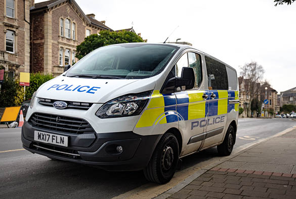 A photo of a UK police van driving down the street.