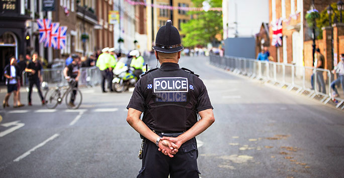 Photograph of a Police Officer patrolling a London street, facing away from the camera
