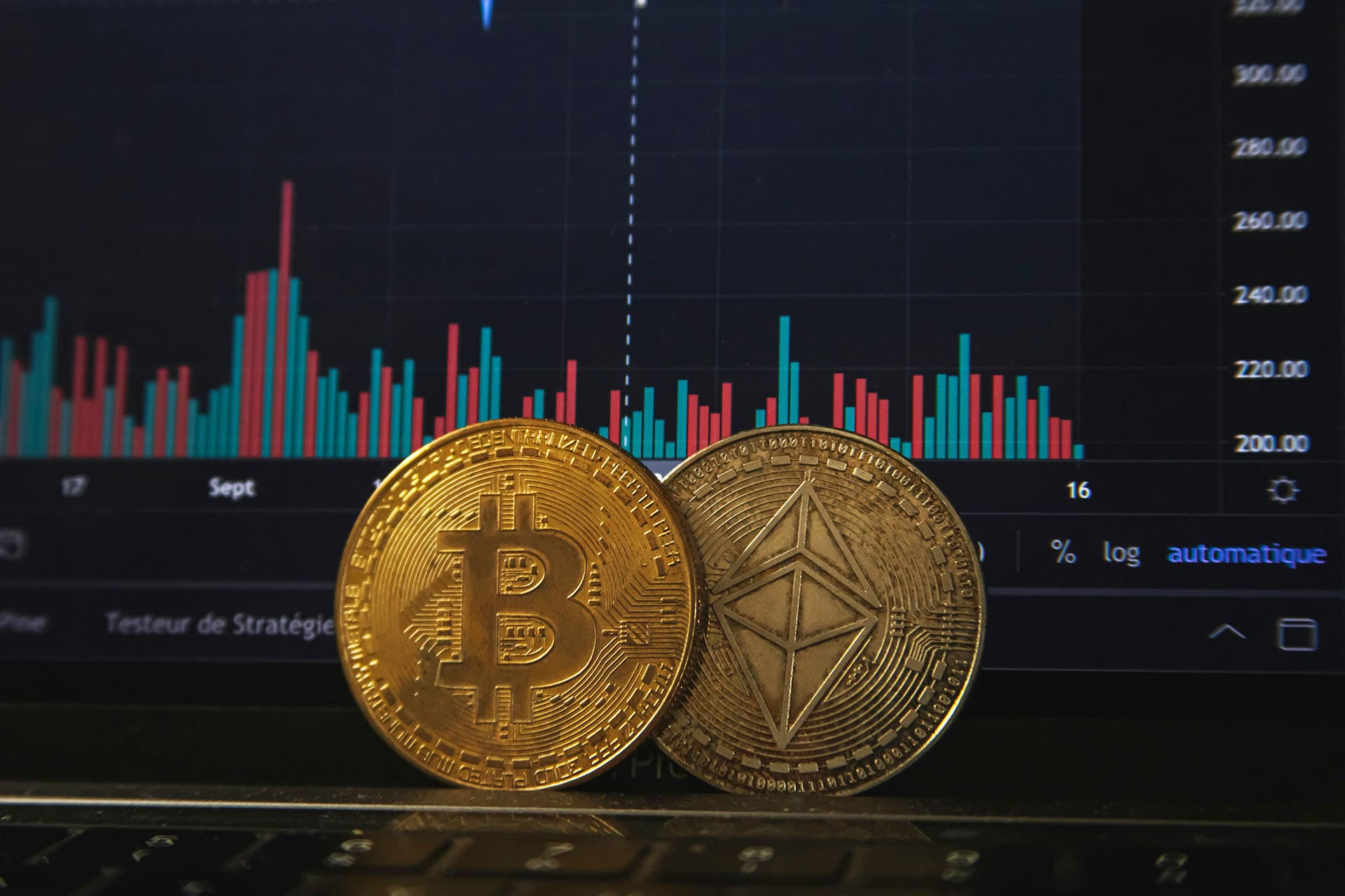 An image of a gold Bitcoin (front and back) in front of a digital financial graph