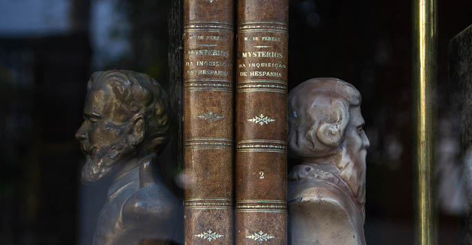 Two old books on a shelf with two statue bookends