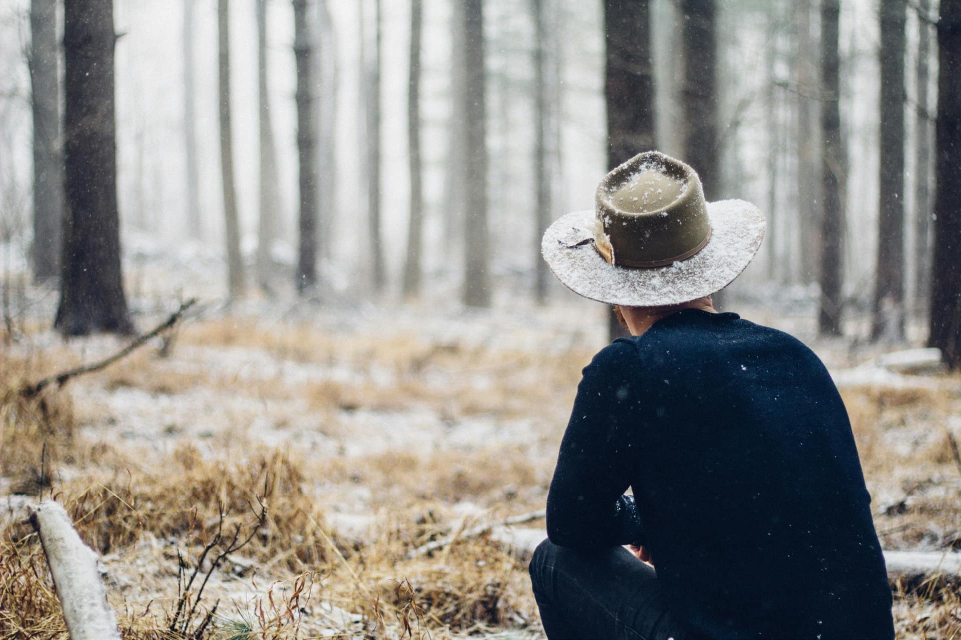 A man sat in the forest staring into the distance.