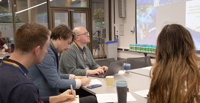 A group of people sat around a table working collaboratively.