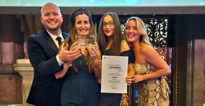 A group of academics at awards night holding up the award they'd won.