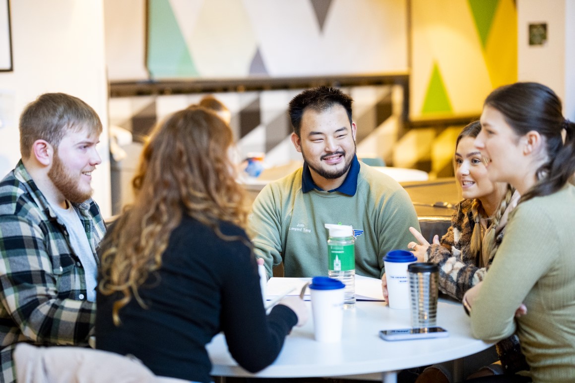 A group of students having a discussion around a table.