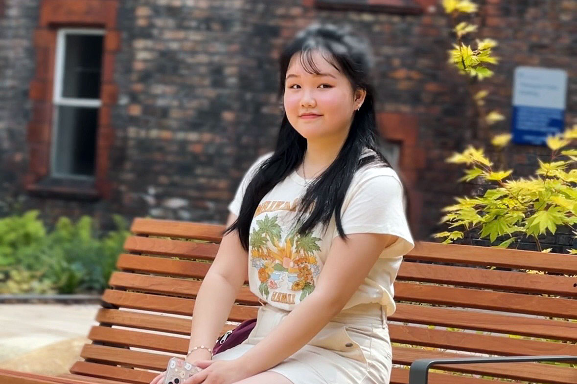 Holly, a student who applied through Clearing, sitting on a bench