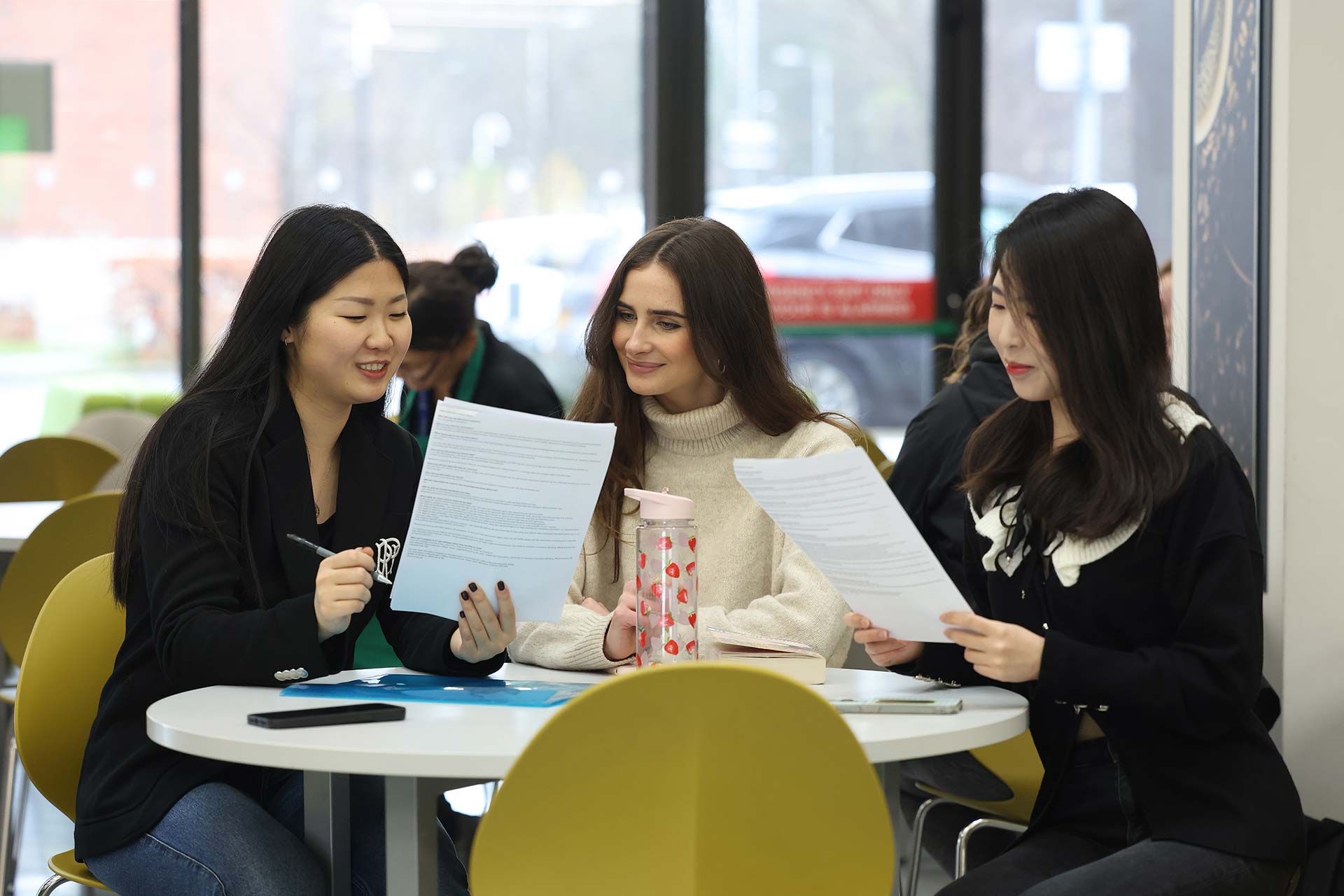 Three students sat round a desk comparing notes during a seminar.