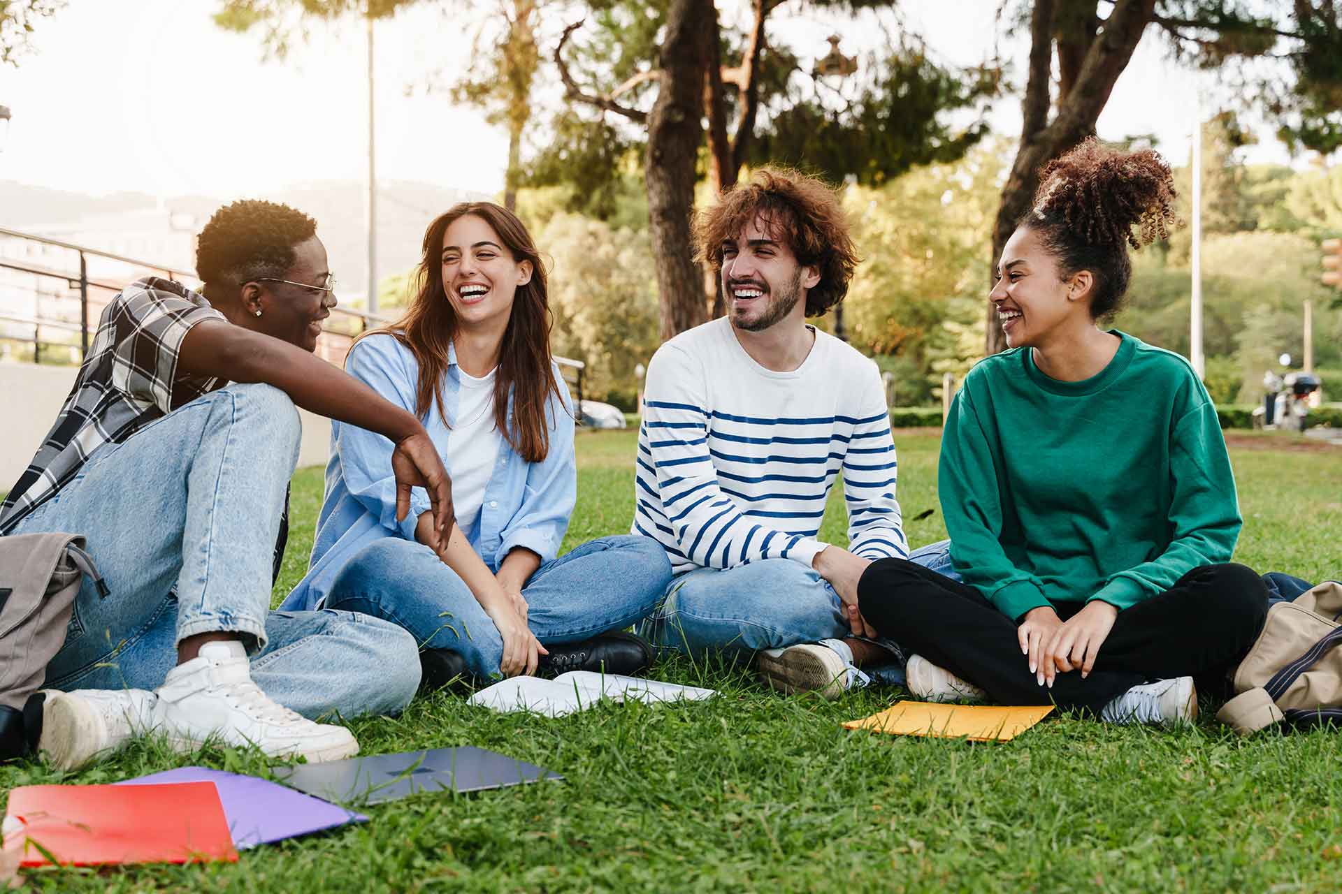 Four students sit chatting while studying on their college campus overseas.