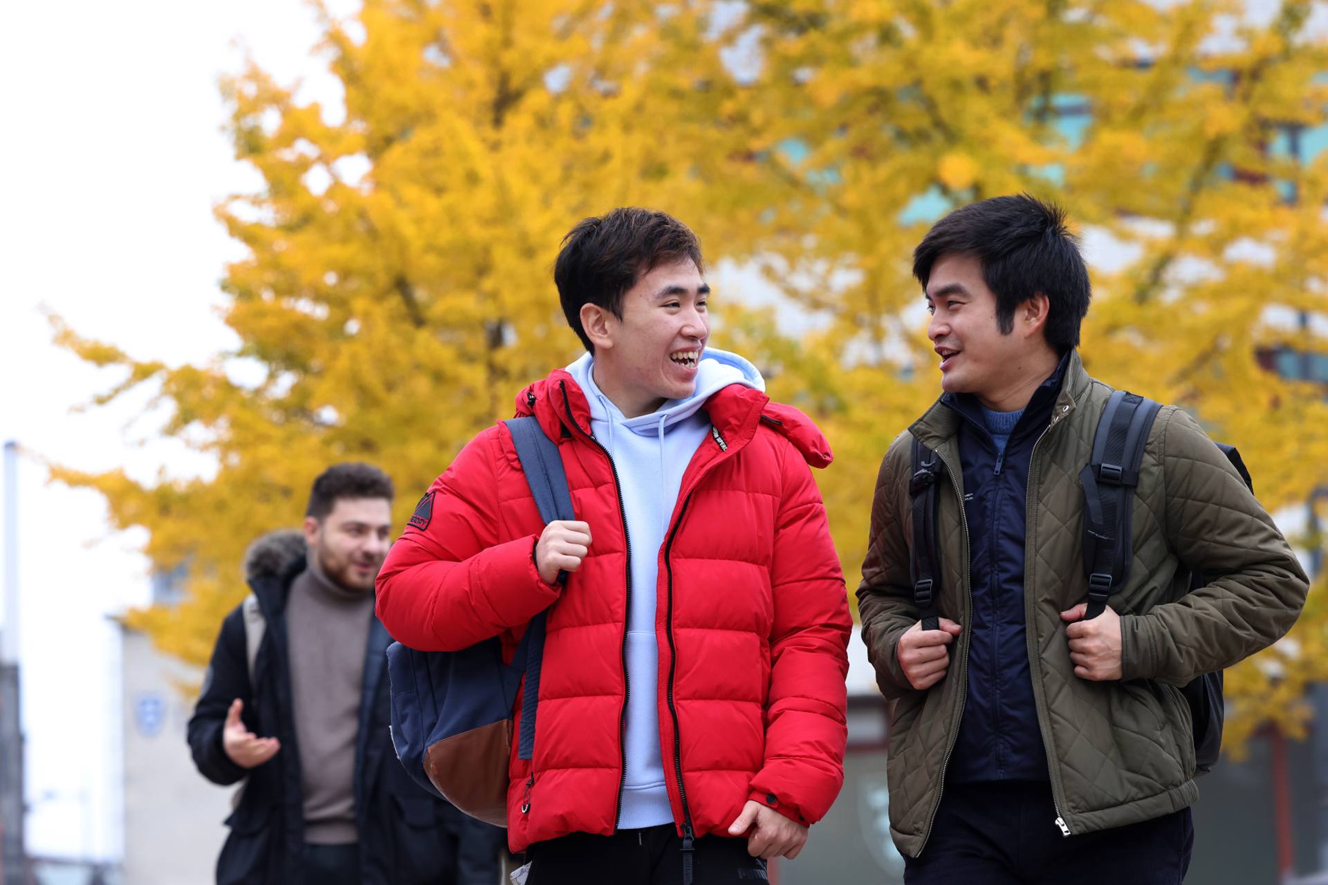 Two students wearing coats and backpacks walk across University Square.