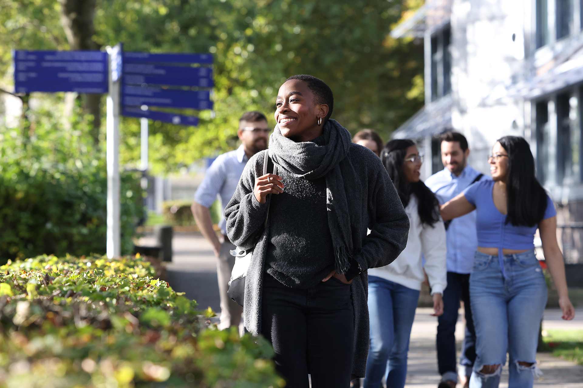 A student walking through campus with a group of other students walking behind.