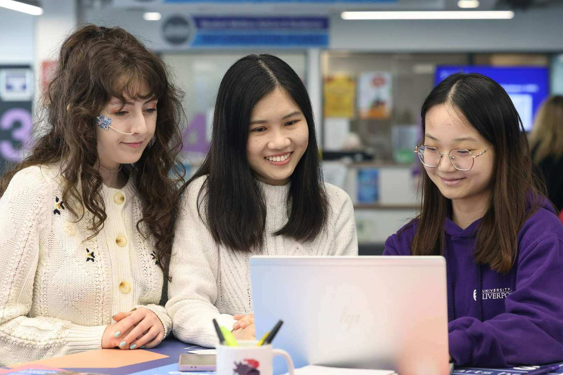 Two students looking at a laptop with a coach from the Careers and Employability service.